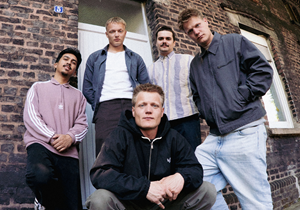 Bandfoto der Band Bruchbude, fünf junge Männer vor einem Backsteingebäude